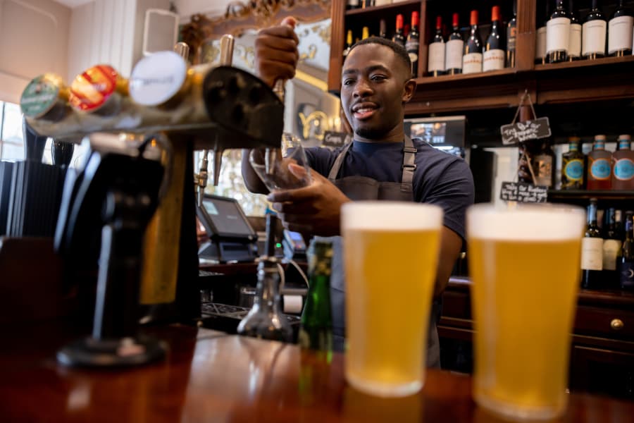 Bartender pours craft beer from bar of craft brewery