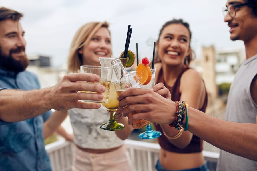 Friends on a rooftop cheering their cocktails