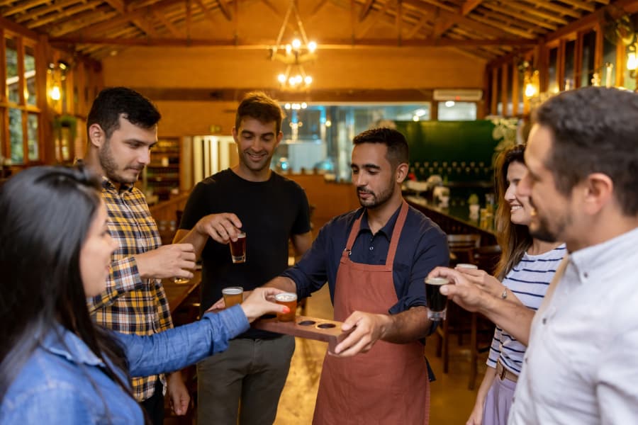 Group of people takes samples of beer from brewer at craft brewery