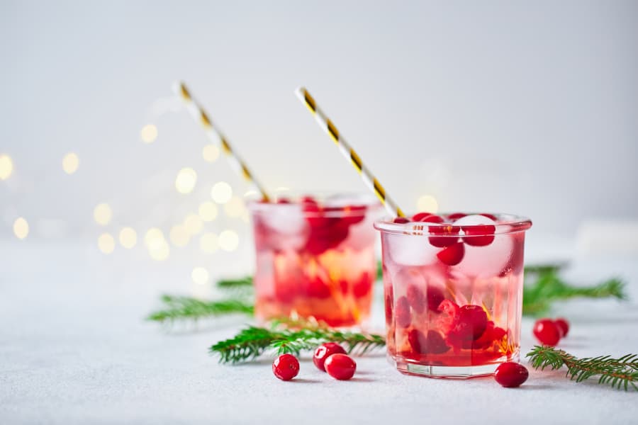 Cocktail with vodka and iced cranberries, garnished with fir branches and glowing garland