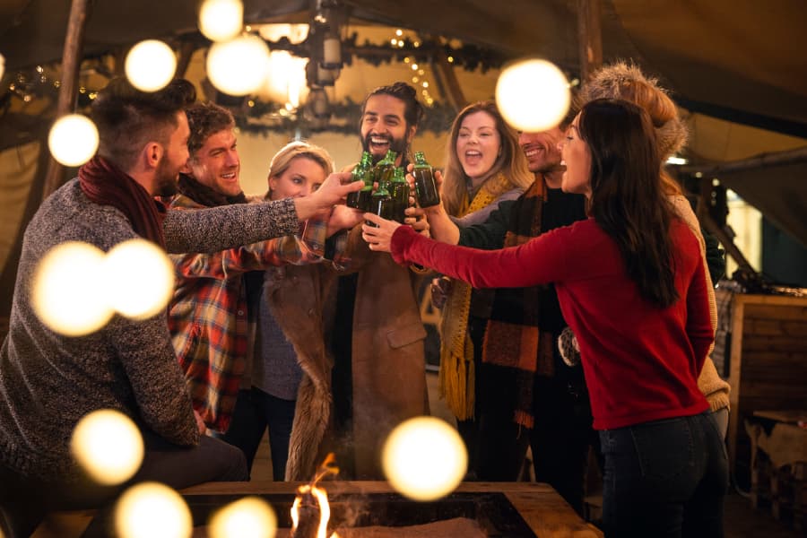 Group of friends toasts with beer bottles at New Years Eve party