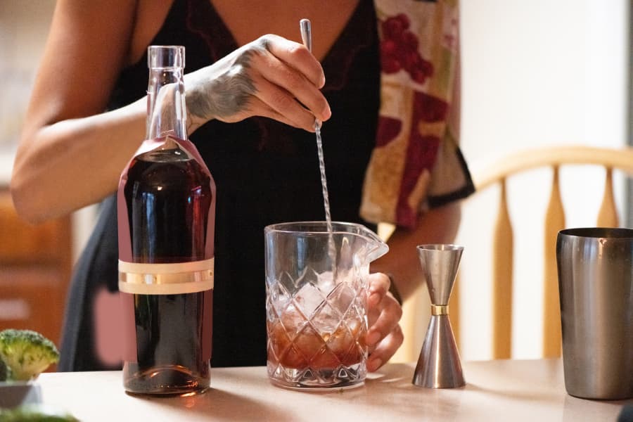 Mixologist enthusiast muddling cherries while creating cocktail at home 